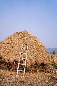 Hay bales on field against clear sky