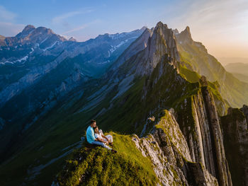 People sitting on rocks against mountain range