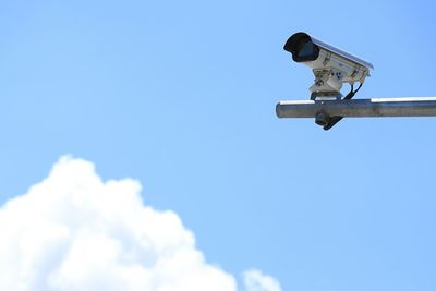 Low angle view of security camera against blue sky