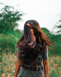  woman flipping hair while standing against trees 