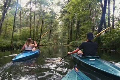 Rear view of friends kayaking in forest