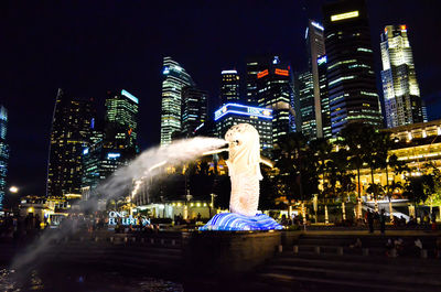 People at illuminated city against sky at night