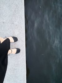 Low section of woman standing by lake