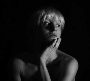 Portrait of young woman against black background