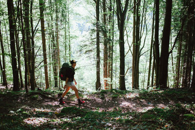 Full length side view of woman walking in forest