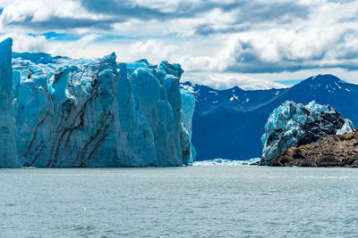 Scenic view of sea by snowcapped mountain against sky