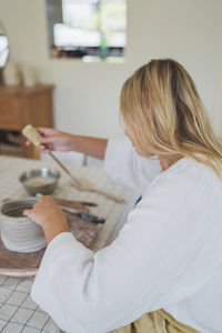 Female pottery artist making a vase in her home studio