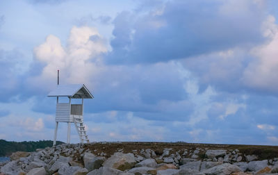 Lighthouse on rock by building against sky