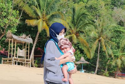 Rear view of mother and daughter on palm trees