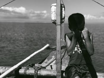 Man sitting by sea against sky