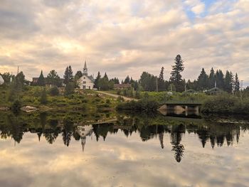 Reflection of trees and buildings on lake against sky