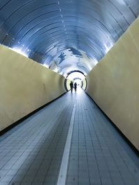 Rear view of people walking in subway tunnel