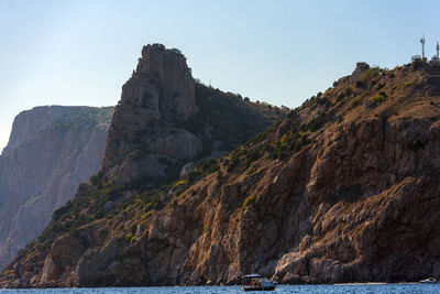 Rock formations by sea against clear sky