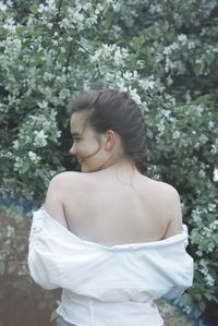 Portrait of young woman standing against plants