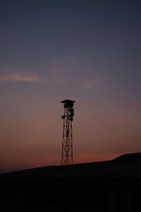 Low angle view of electricity pylon against sky during sunset