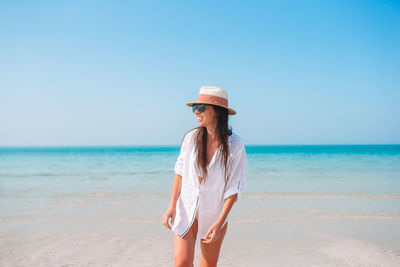 Woman standing on beach against clear sky