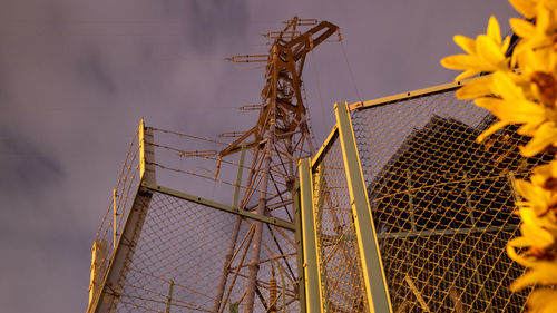 Low angle view of metallic fence against sky