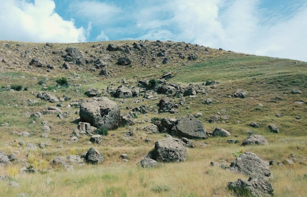 landscape, sky, tranquility, tranquil scene, grass, nature, scenics, field, beauty in nature, non-urban scene, rock - object, cloud - sky, rock formation, cloud, mountain, day, remote, rock, outdoors, rural scene, no people, hill, geology, physical geography, horizon over land, non urban scene, idyllic, grassy, travel destinations, plant, green color, growth