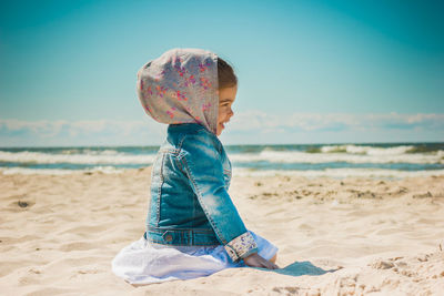 Smiling girl kneeling at beach