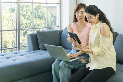 Young woman using mobile phone while sitting on sofa