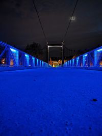 Surface level of empty road against blue sky at night