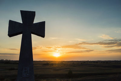 Cross on field against sky during sunset