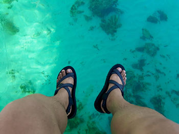 Low section of man wearing sandals over sea