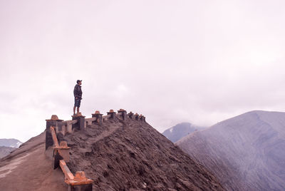 Man standing on rock against sky