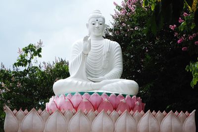 Low angle view of buddha statue against trees