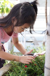 Close-up of girl taking picture of plants