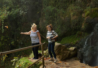 Full length of female friends standing by rock formations