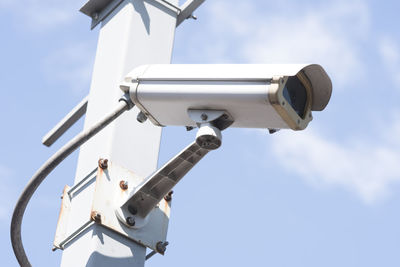 Low angle view of security cameras against sky