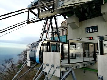 Overhead cable cars at station against sky