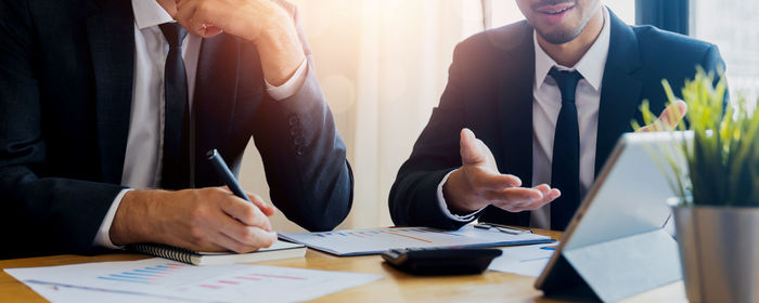 Midsection of business people working on table