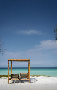 Empty deck chairs on beach against sky