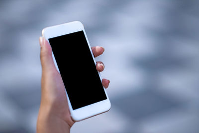 Close-up of human hand holding smart phone outdoors