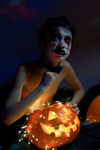 Close-up of a boy with pumpkin in background