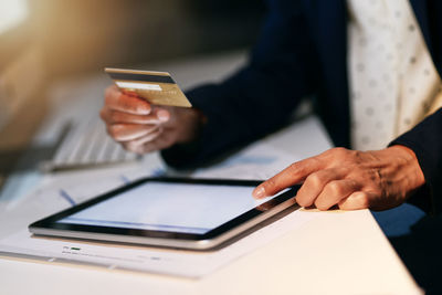 Midsection of businessman using mobile phone at table