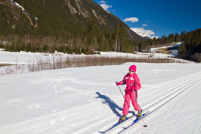 Full length portrait of cute little girl enjoying cross-country skiing