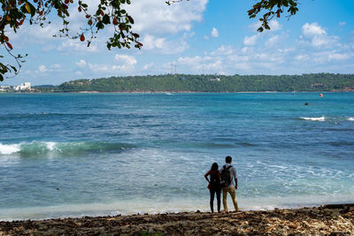 Friends on beach against sky