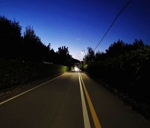 Road amidst trees against sky at dusk