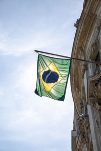 Low angle view of brazil flag on building against sky