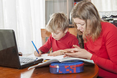 Front view of people using laptop on table