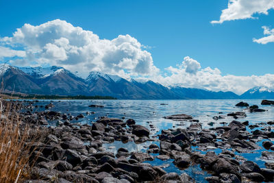 Scenic view of sea by snowcapped mountains against sky