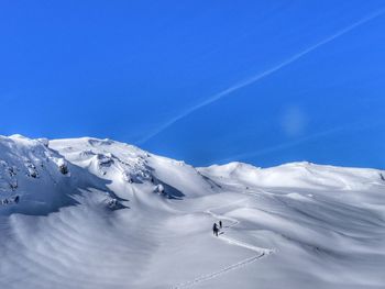 Scenic view of snow covered mountain against blue sky