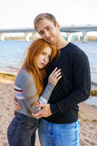 Young couple is standing on the river bank hugging