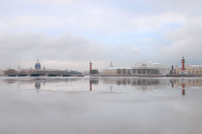 Reflection of buildings in city against cloudy sky