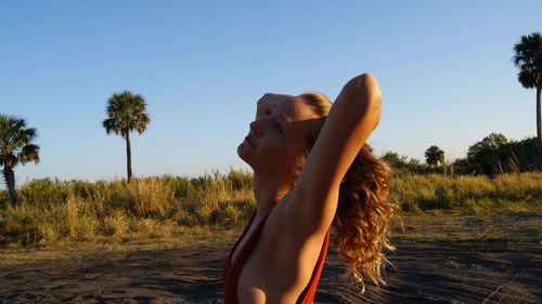 Woman standing by palm tree against clear sky