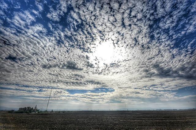 sky, landscape, field, cloud - sky, tranquility, tranquil scene, cloudy, rural scene, scenics, nature, cloud, beauty in nature, electricity pylon, power line, agriculture, weather, fuel and power generation, outdoors, no people, farm