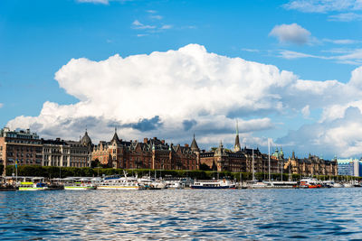 Panoramic view of buildings by sea against cloudy sky